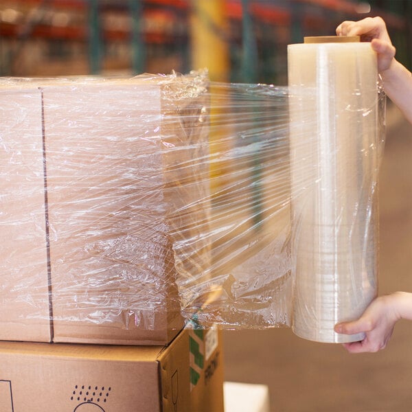 A woman holding a box of Lavex Pro heavy-duty hand pallet wrap.