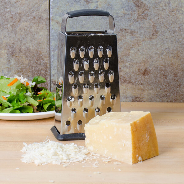 A Tablecraft stainless steel box grater next to a plate of salad with lettuce and carrots.