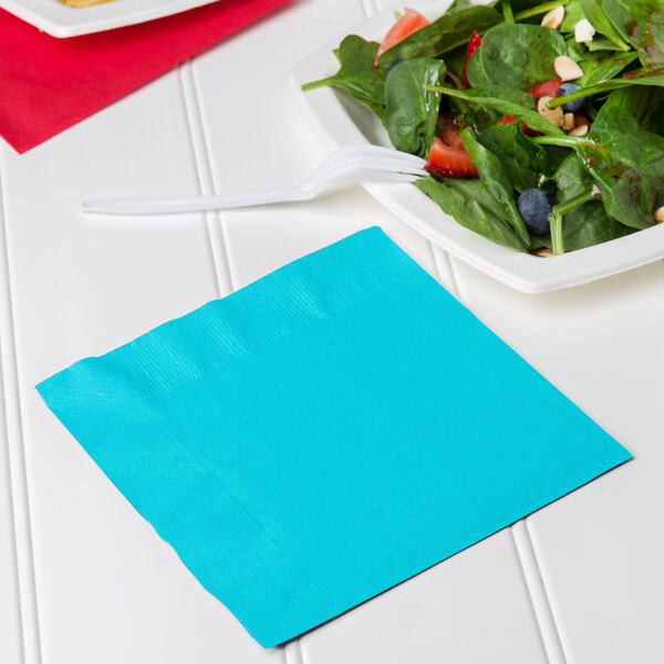 A Bermuda blue luncheon napkin with a fork and salad plate.