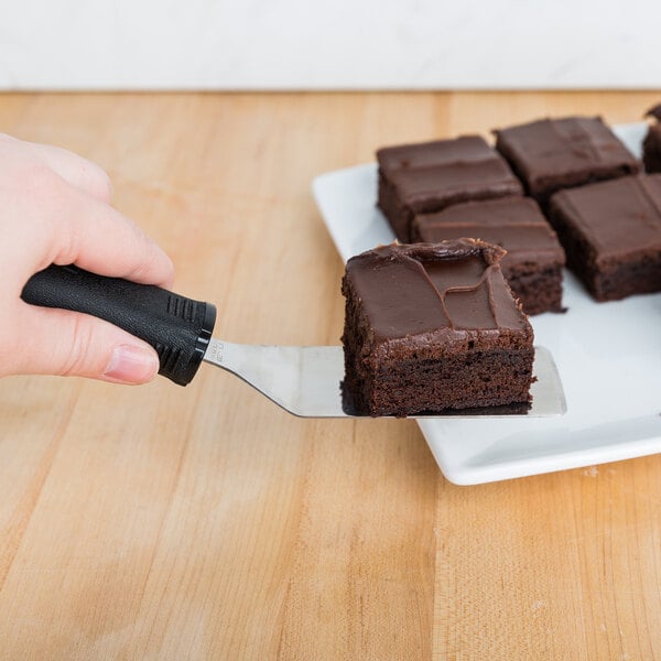 A hand using a Tablecraft FirmGrip slotted mini turner to serve a brownie