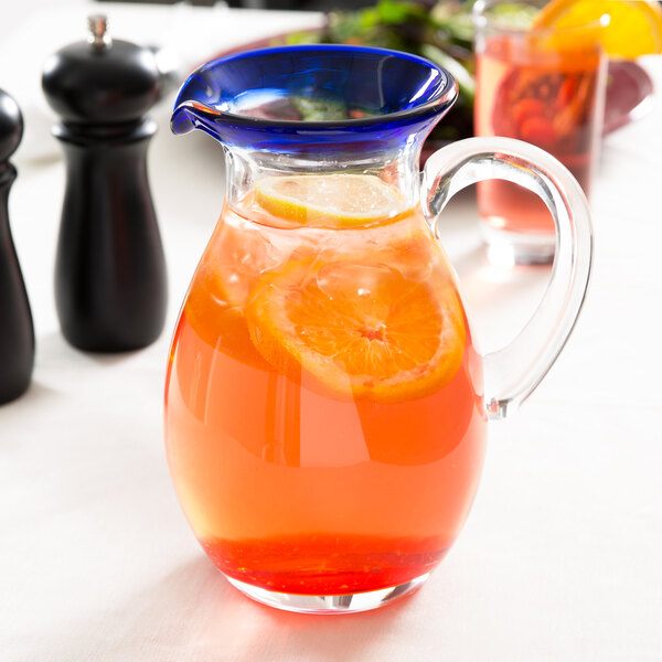 A Libbey Aruba pitcher filled with orange juice and a slice of orange on the rim.