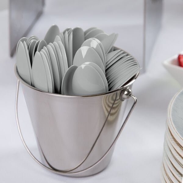 A bucket filled with Creative Converting Shimmering Silver plastic spoons.