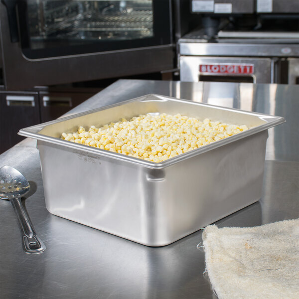 A Vollrath stainless steel steam table pan filled with popcorn on a counter.