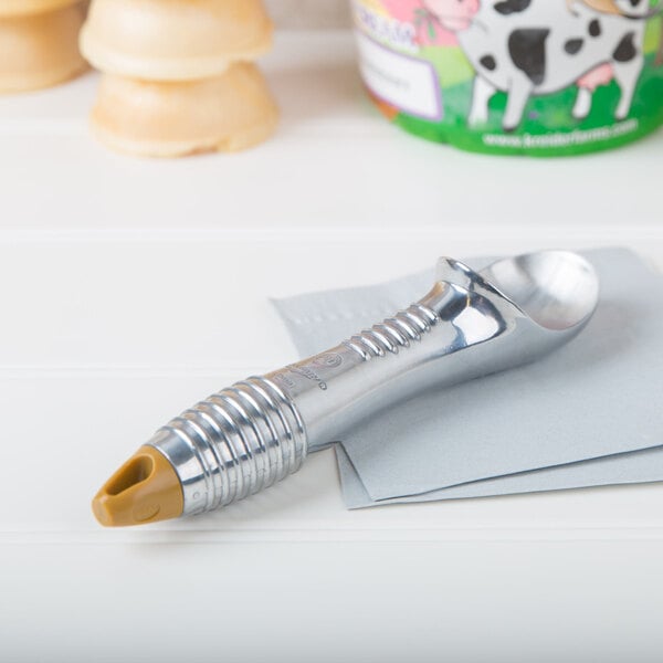 A silver metal Vollrath ice cream scoop on a white surface.