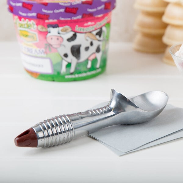 A Vollrath aluminum ice cream scoop on a white surface.