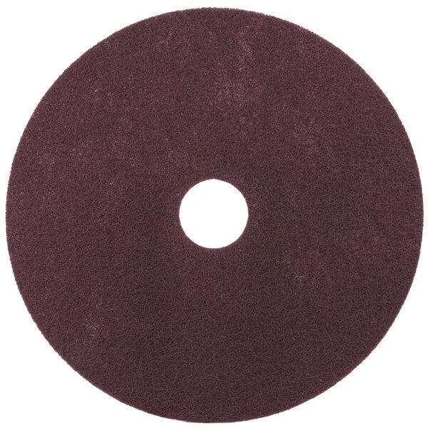 A brown circular 3M Scotch-Brite surface preparation pad with a hole in the middle.