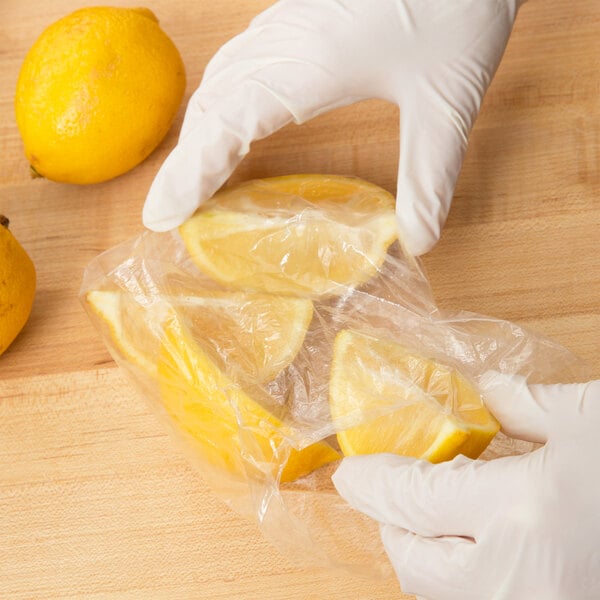 A gloved hand putting lemon wedges in an Inteplast Group plastic bag.
