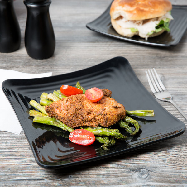 A black GET Milano melamine square plate with food on it including tomatoes, asparagus, and a piece of meat with a tomato on top.