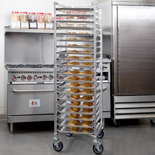 A tall, metal, wheeled rack holding multiple trays of baked goods in a commercial kitchen setting.