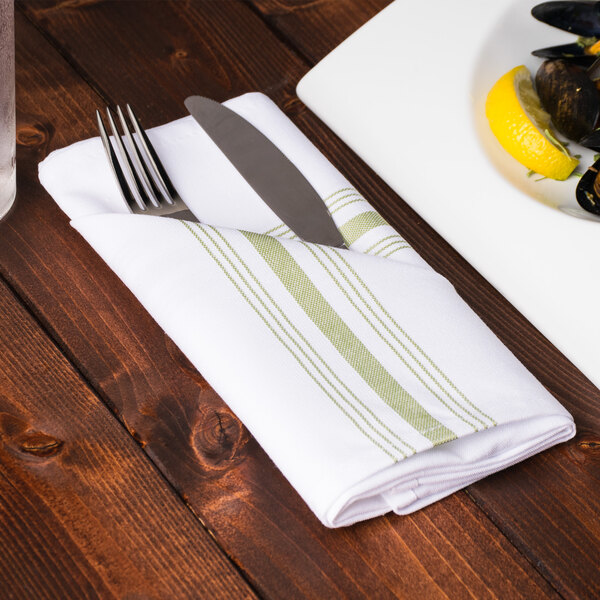 A fork and knife wrapped in a Snap Drape Bistro striped cloth napkin on a plate of food.