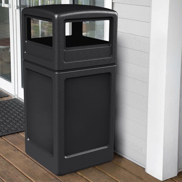 A black Commercial Zone PolyTec waste container on a porch.
