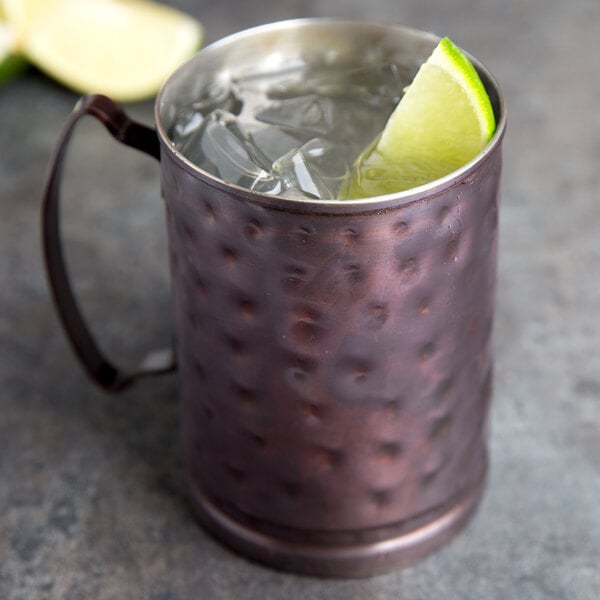 A Libbey hammered antique copper Moscow Mule mug filled with ice and a lime wedge.