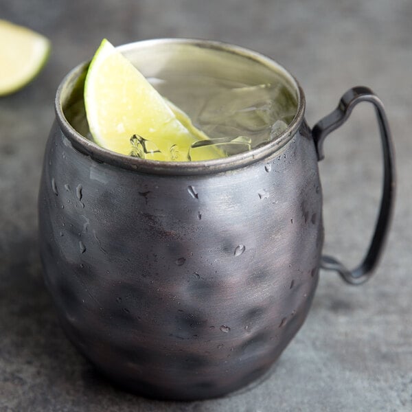 A Libbey hammered antique copper Moscow mule mug filled with a lime wedge in it.