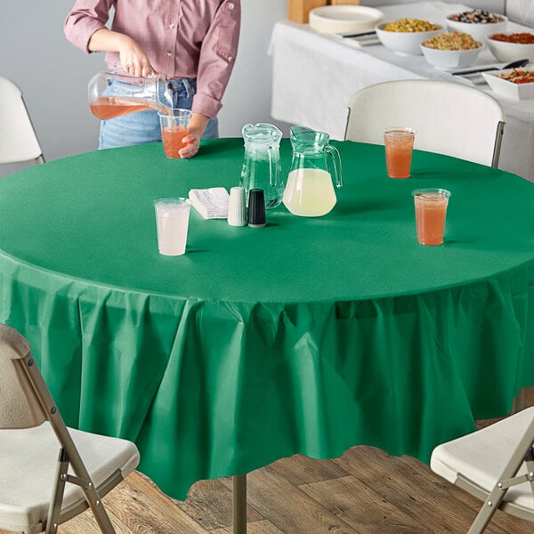 A table with bowls of food and a glass of orange liquid on a table with an Emerald Green OctyRound tablecloth.