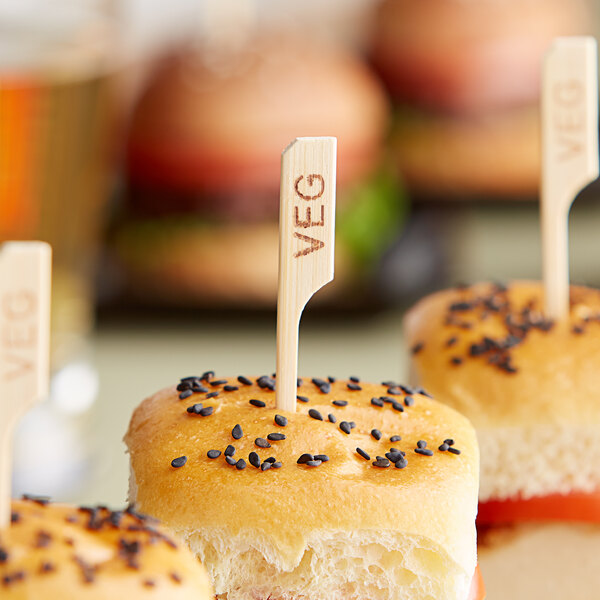 A group of small sandwiches with Tablecraft wooden veggie picks in them.