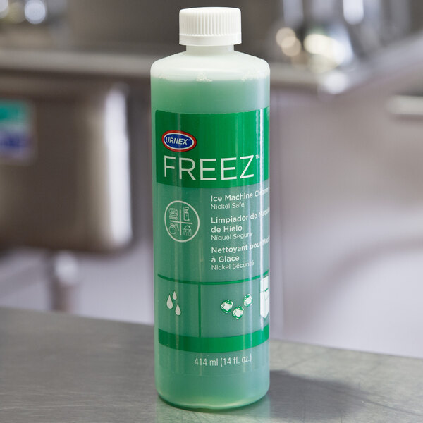 A green Urnex Freez bottle with white text on a counter.