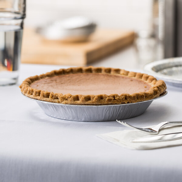 A Baker's Mark extra deep foil pie pan with a pie in it on a table.