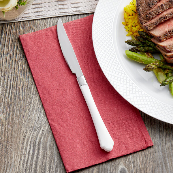 A Visions white plastic knife on a plate of meat.