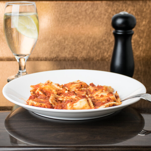 A Chef & Sommelier Infinity white bone china plate with pasta and sauce on a table.