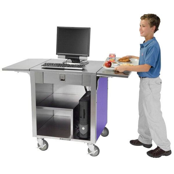 A boy standing next to a purple Lakeside cash register stand with a computer on it.