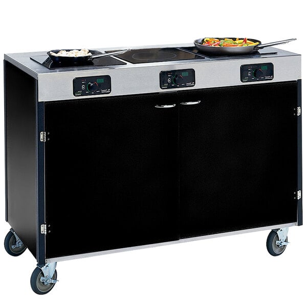 A black and silver Lakeside mobile cooking cart with three induction burners, one with pans and vegetables on it.