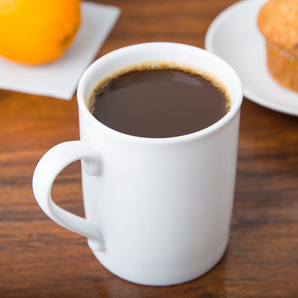 A white porcelain Arcoroc mug filled with coffee on a table.