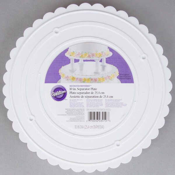 A white plastic Wilton cake separator plate with a scalloped edge.