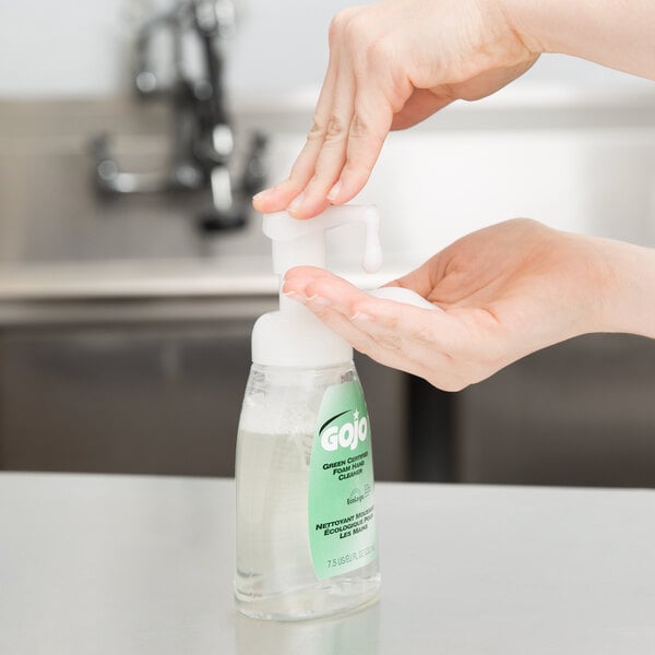 A hand using a GOJO Green Certified Fragrance Free foaming hand soap pump.