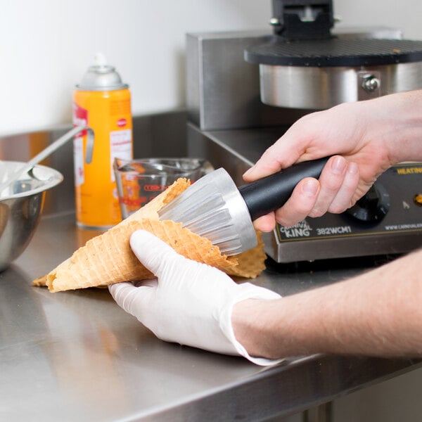 A person using a Carnival King waffle cone mandrel to wrap a waffle cone.