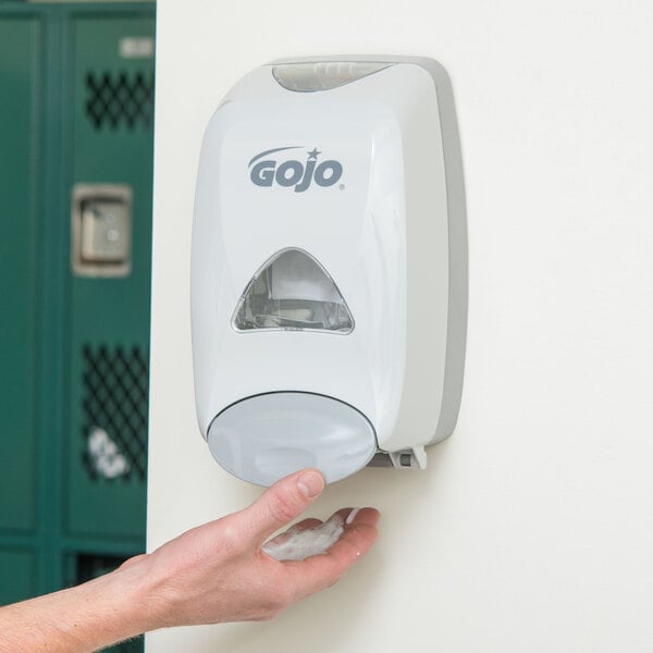 A person using a GOJO Dove Gray manual hand soap dispenser.