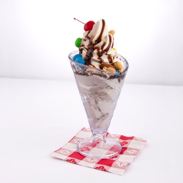 A clear plastic waffle cone cup filled with a sundae.
