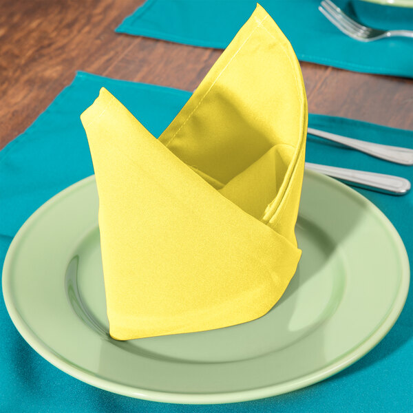 A folded yellow Intedge cloth napkin on a plate.