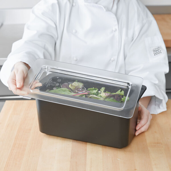 A chef holding a clear plastic container with food in it.