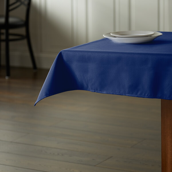 A table with a royal blue Intedge tablecloth and a plate on it.