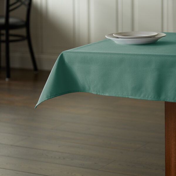 A table with a seafoam green Intedge tablecloth and a plate on it.