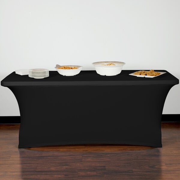 A black Snap Drape spandex table cover on a table with white bowls of food.