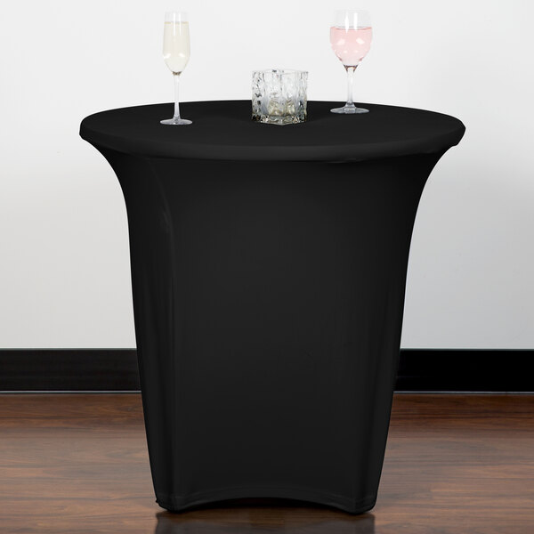 A black Snap Drape Contour spandex table cover on a table with two glasses on it.