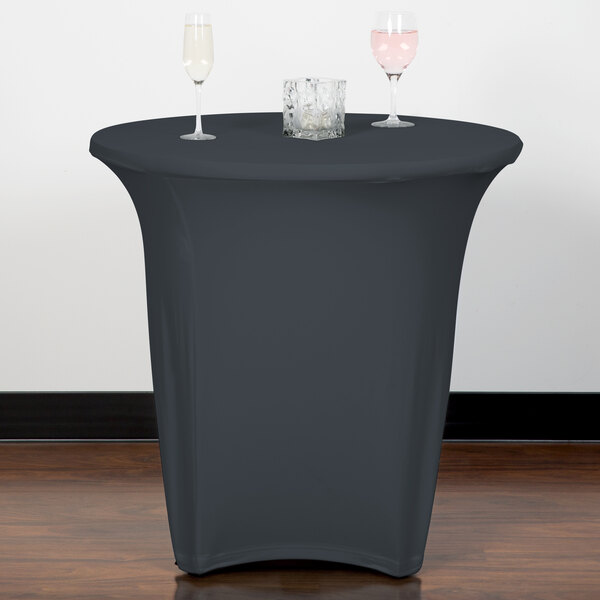 A table with a Snap Drape charcoal spandex table cover and wine glasses on it.