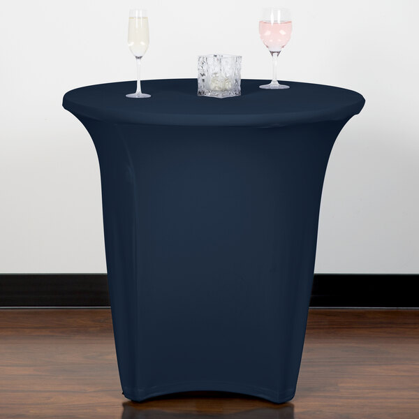A navy blue Snap Drape Contour spandex table cover on a round table with wine glasses on it.