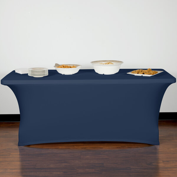 A navy Snap Drape spandex table cover on a table with food in white bowls.