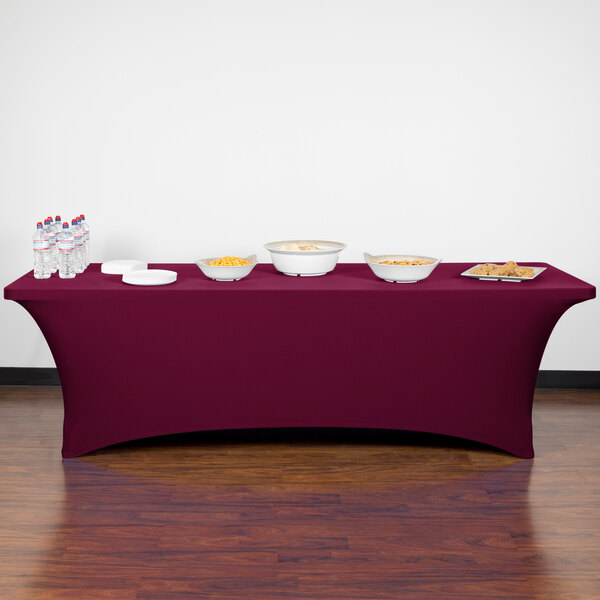 A burgundy Snap Drape spandex table cover on a table with food and bowls.