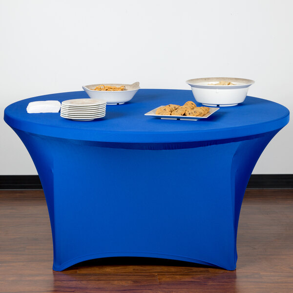 A royal blue Snap Drape spandex table cover on a table with plates of food.