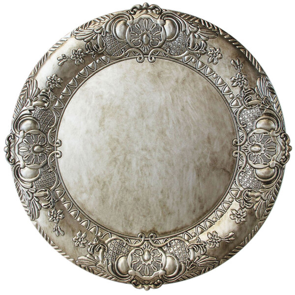 A close up of a round silver Charge It by Jay plastic charger plate with an ornate design.