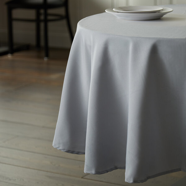 A table with a gray Intedge polyester tablecloth and a plate on it.