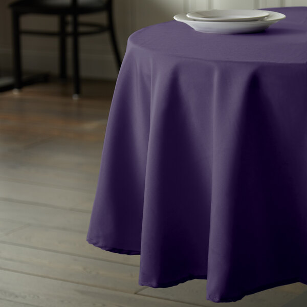A table with an Intedge purple polyester table cover with a white plate on it.