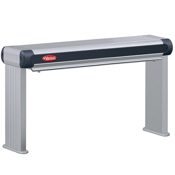 A grey rectangular Hatco strip warmer with black and red remote controls on a metal shelf.