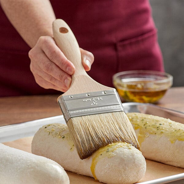 A person using an Ateco Boar Bristle Pastry/Basting Brush to paint food.