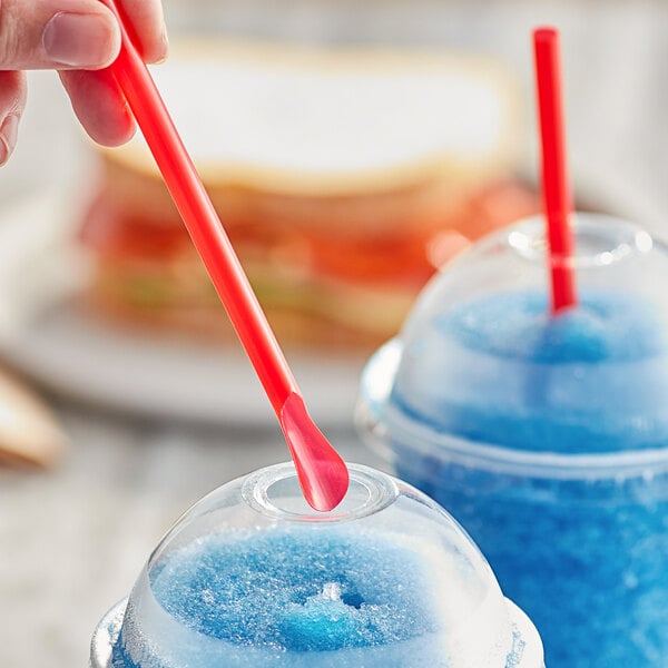 A person holding a Choice red jumbo spoon straw in a cup of blue liquid.