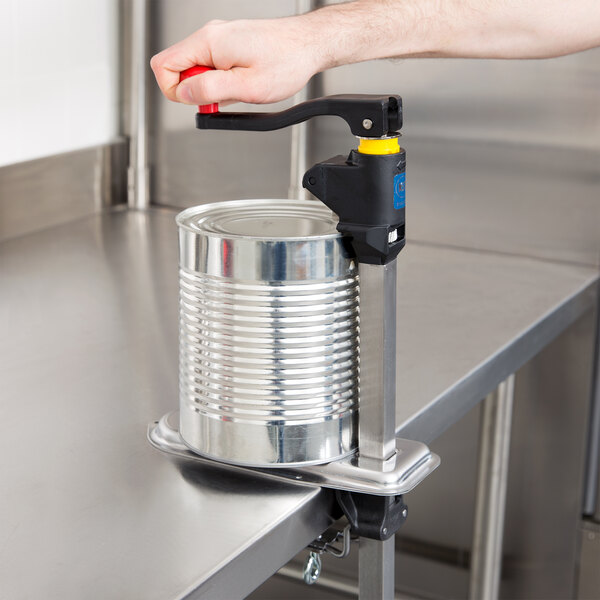 A person using a Vollrath Redco EaziClean medium-duty can opener to open a can on a counter.
