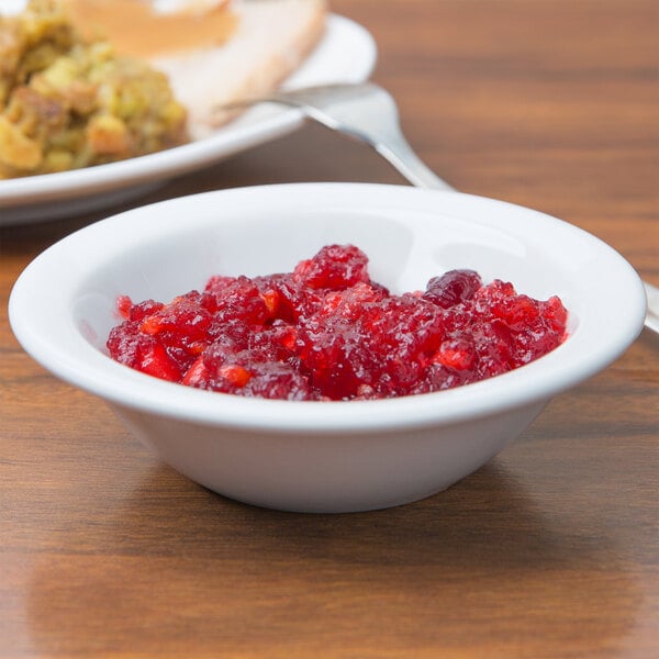 A Tuxton Colorado narrow rim china bowl filled with cranberry sauce on a table with turkey plates.